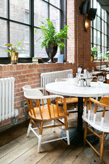 trendy and urban wooden restaurant chairs and table, brick walls, marble table, hipster coffee shop