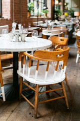 trendy and urban wooden restaurant chairs and table, brick walls, marble table, hipster coffee shop