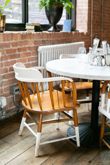 trendy and urban wooden restaurant chairs and table, brick walls, marble table, hipster coffee shop