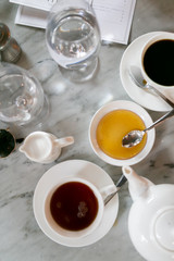 Top view of tea and coffee cup at cafe with honey and water cups, marble table