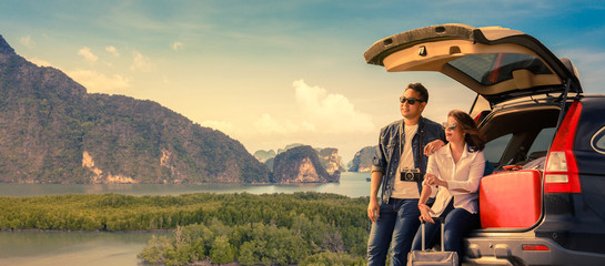 Asian couple Man with vintage camerra and woman sitting on back of car  travel to mountain and lake...