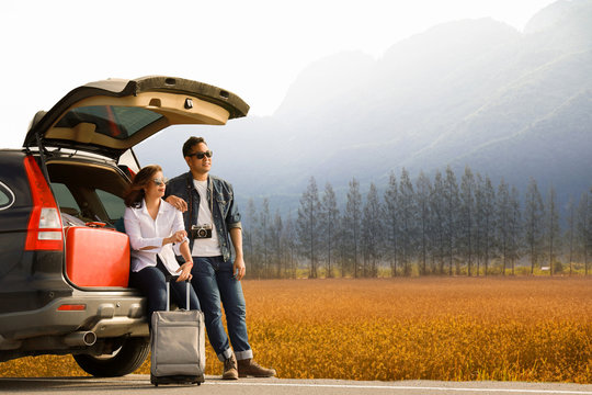 Asian couple Man with vintage camerra and woman sitting on back of car  travel to mountain and lake in holiday with car road trip