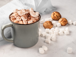 Hot chocolate in a gray mug with cookies on a concrete surface.