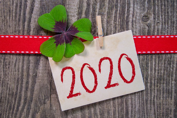 Wooden hang tag with four leaf clover and with happy new year 2020 on wooden weathered background