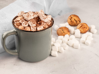 Hot chocolate in a gray mug with cookies on a concrete surface.