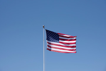 The US flag waving under a bright blue sky on a California summer day