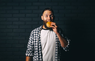 Hungry man with beard eating a hamburger
