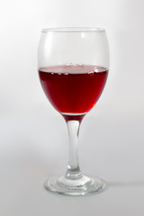 A cup glass of red wine on with a shadow on the right side.