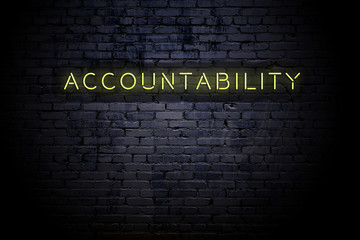 Highlighted brick wall with neon inscription accountability