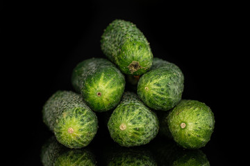Group of six whole fresh pickling cucumber pyramid isolated on black glass