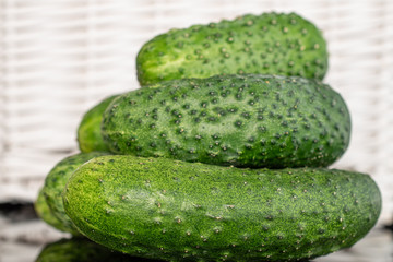 Group of three whole fresh pickling cucumber with braided rattan behind