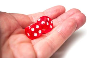 Closeup of red dice in hand on white background