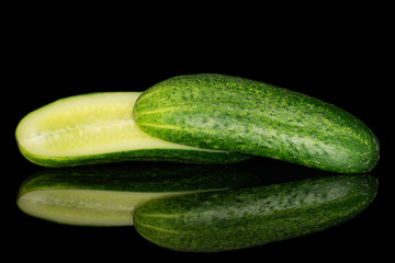 Group of two halves of fresh green pickling cucumber one sliced isolated on black glass