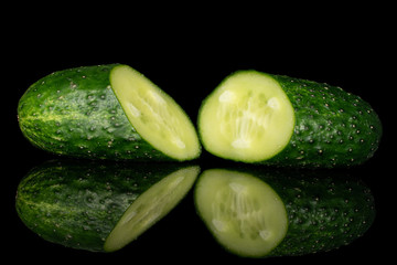 Group of two halves of fresh green pickling cucumber isolated on black glass