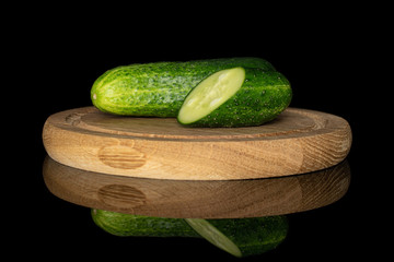 Group of one whole one half of fresh green pickling cucumber on bamboo plate isolated on black glass