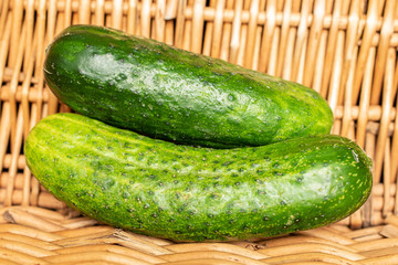 Group of three whole fresh green pickling cucumber with braided rattan behind
