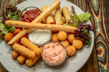 Allsorts of fried snacks with two different sauces on black background