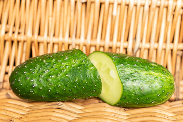 Group of two halves of fresh green pickling cucumber with braided rattan behind