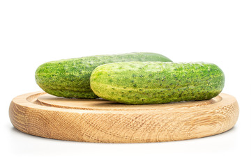 Group of two whole fresh green pickling cucumber on bamboo plate isolated on white background