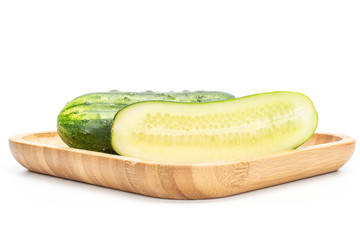 Group of one whole one half of fresh green pickling cucumber on wooden square plate isolated on white background