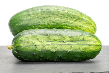 Group of two whole fresh green pickling cucumber on grey stone isolated on white background