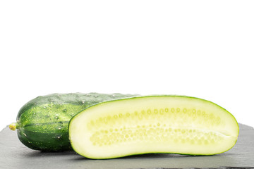 Group of one whole two halves of fresh green pickling cucumber on grey stone isolated on white background