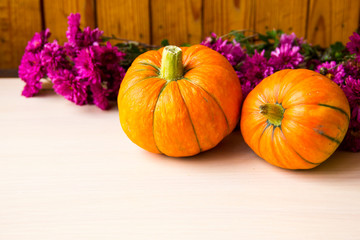 Autumn background with pumpkins and chrysanthemum flowers on wooden background, copy space. Happy Thanksgiving Day Background. Concept of Halloween. Pumpkin for autumn Harvest Festival. Autumn scene.