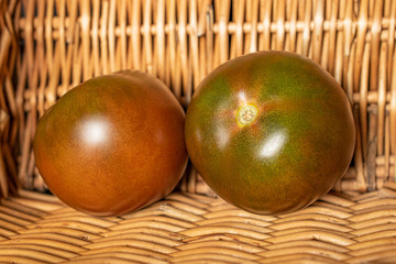 Group of two whole fresh green red tomato with braided rattan behind