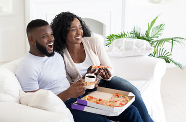 Obraz na płótnie Canvas African american couple eating pizza and drinking coffee at home