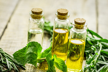herbal extract in glass bottles, mint and rosemary for spa on wooden table background
