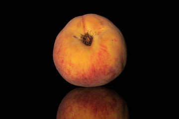 One whole fresh fuzzy peach isolated on black glass