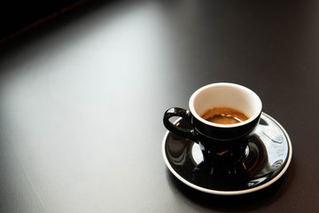 hot espresso in black cup of coffee on greasy black background