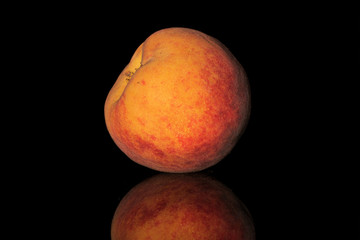 One whole bright fresh fuzzy peach isolated on black glass