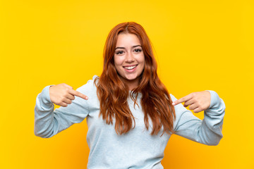 Teenager redhead girl over isolated yellow background proud and self-satisfied