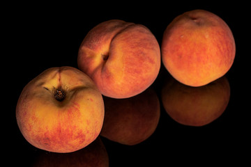 Group of three whole bright fresh fuzzy peach isolated on black glass