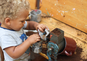 Little boy playing with coffee grounds in a dramatic play, sensory play, garden kitchen