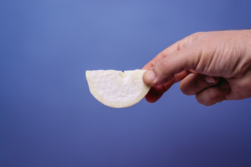 A slice of fresh goat cheese in a male hand