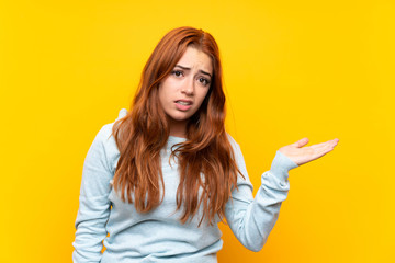 Teenager redhead girl over isolated yellow background unhappy for not understand something