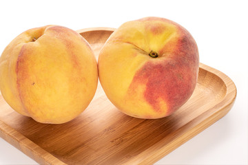 Group of three whole fresh fuzzy peach on bamboo plate isolated on white background