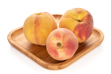 Group of two whole fresh fuzzy peach on bamboo plate isolated on white background