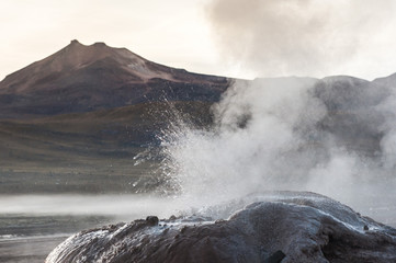 Detail of active geyser formation at El Tatio, Atacama, Chile. Active geysers comes out of the ground. Hot vapor erupting activity, thick flume of steam. Tourists watching geyser in the Los Géiseres 