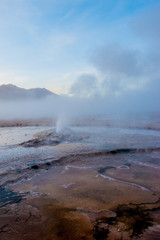 Fototapeta na wymiar El Tatio, Atacama, Chile. Active geysers comes out of the ground. Hot vapor erupting activity, thick flume of steam. Tourists watching geyser in the Los Géiseres del Tatio area in the Atacama Desert