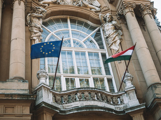 The waving European and Hungarian flag in front of an old building.