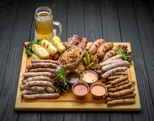Grilled sausages with glass of beer on a wooden table
