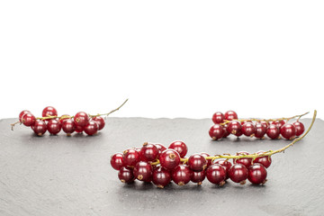 Lot of whole fresh dark redcurrant on grey stone isolated on white background