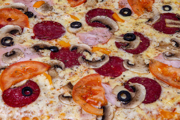 Pizza closeup background with salami, mushrooms, tomatoes and olives