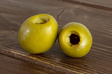 Group of two whole pitted green olive on brown wood