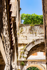 Naklejka premium Stone arch, characteristic architecture in Dalmatia, remains of the Roman Empire, blue sky, summer time and holidays in Split, Dalmatia, Croatia 