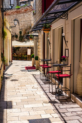 Picturesque narrow stone street with bars, tables, lantern in Roman town, summer time and holidays, Split, Dalmatia, Croatia 