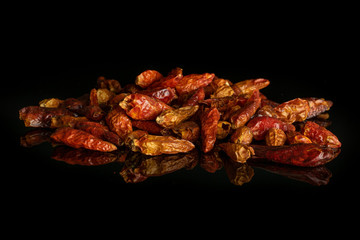 Lot of whole dry red chili pepper peperoncino stack isolated on black glass